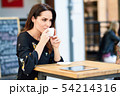 Middle-aged woman drinking coffee in an urban cafe 54214316