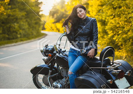 attractive brunette motorcyclist sits on a motorcycle. 54216546