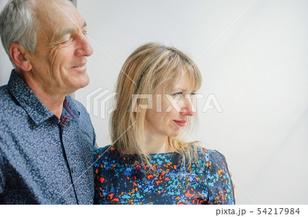 Portrait of Couple with Age Difference Standing near Opened Window inside the House. Elderly Man is Portrait of Couple with Age Difference Standing near Opened Window inside the House. Elderly Man is 54217984
