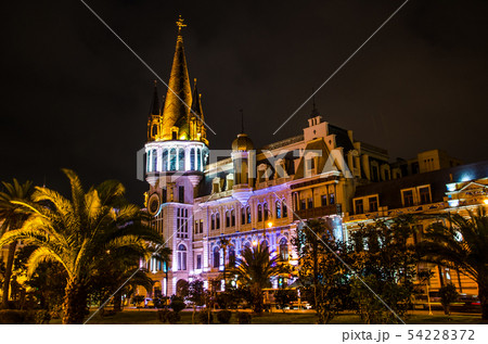 Night view of illuminated Batumi Astronomical Clock Tower building with palm tree 54228372