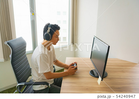 [eスポーツのイメージ] モニタの前でオンライン対戦ゲームの練習風景 or ゲーム開発エンジニア 54240947