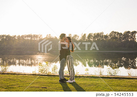 Romantica, nature and people concept - young couple kissing on the beach of lake and hugging Romantica, nature and people concept - young couple kissing on the beach of lake and hugging 54245553