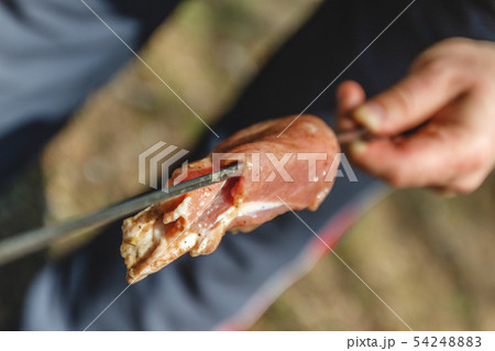 man stringing meat on a skewer. Close-up. 54248883