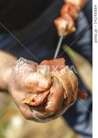 man stringing meat on a skewer. Close-up. 54248884