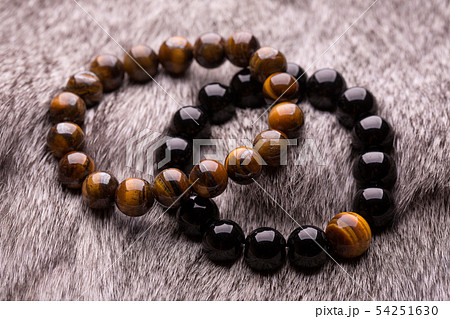 Two bracelets of round stones on gray fur. 54251630
