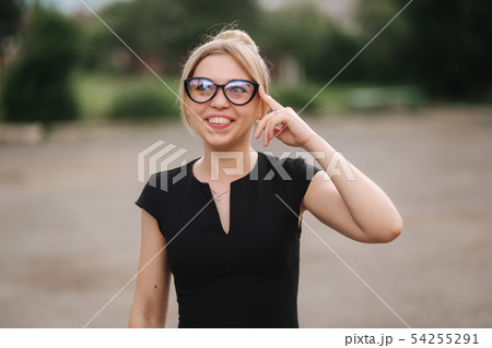 Young attractive female techer in black dress with sunglasses standing outside. Background of school Young attractive female techer in black dress with sunglasses standing outside. Background of school 54255291