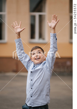 Happy boy jump and raises hands up. Background of school 54255572