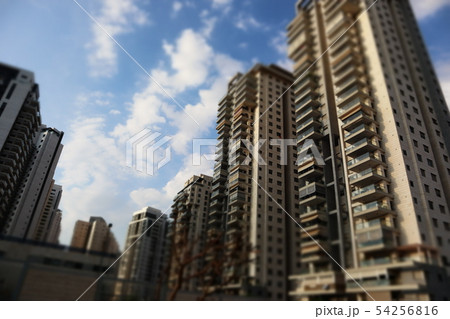 Looking up multi-story buildings to a blue, cloudy sky 54256816