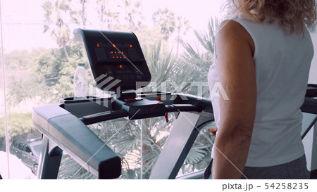 Senior woman is engaged on a treadmill in the gym against the background of the panoramic window.  54258235