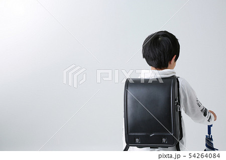 白背景にランドセルを背負った小学生の男の子が傘を持っている 54264084