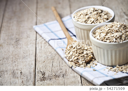 Oat flakes in ceramic bowls and wooden spoon on Oat flakes in ceramic bowls and wooden spoon on 54271509