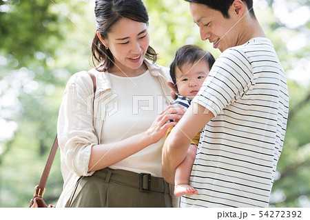 赤ちゃんを抱く若い夫婦 子育て 育児 家族 公園 初夏の写真素材