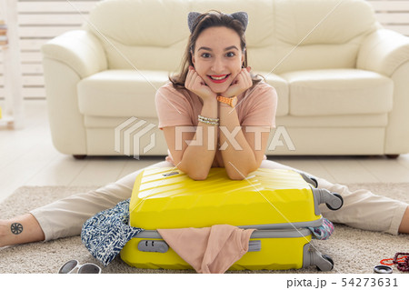 Summer holidays, voyage and traveler concept - Young beautiful woman collects a suitcase on a summer 54273631