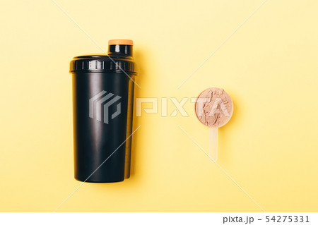Scoop of whey protein powder near shaker Scoop of whey protein powder near shaker 54275331