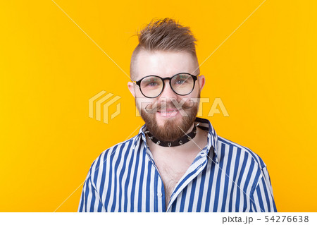 Young positive trendy man hipster with a mustache beard and fetish necklace in shirt posing on a 54276638