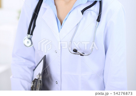 Stethoscope at female doctor breast at hospital office. Unknown physician's hands close-up. Medicine 54276873