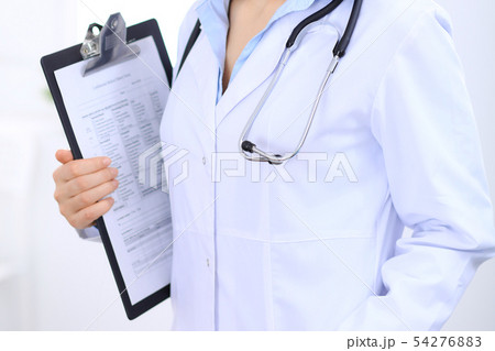 Stethoscope at female doctor breast at hospital office. Unknown physician's hands close-up. Medicine 54276883