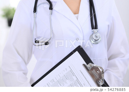 Stethoscope at female doctor breast at hospital office. Unknown physician's hands close-up. Medicine Stethoscope at female doctor breast at hospital office. Unknown physician's hands close-up. Medicine 54276885