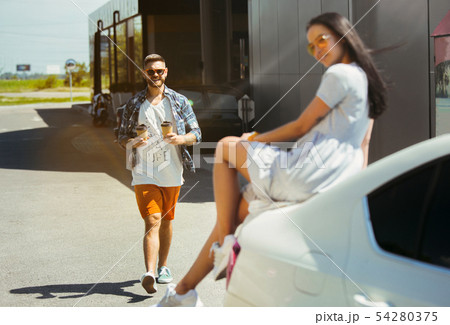 Young couple preparing for vacation trip on the car in sunny day Young couple preparing for vacation trip on the car in sunny day 54280375