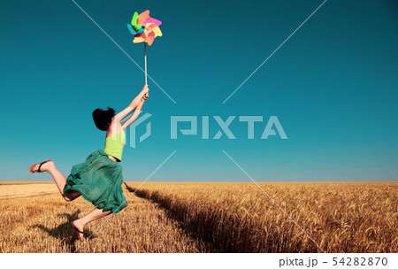girl jumping with pinwheel over wheat field girl jumping with pinwheel over wheat field 54282870