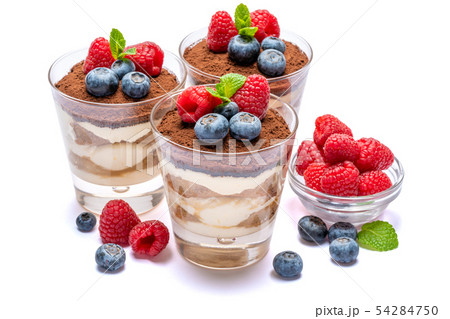 Classic tiramisu dessert with blueberries and raspberries in a glass isolated on a white background Classic tiramisu dessert with blueberries and raspberries in a glass isolated on a white background 54284750
