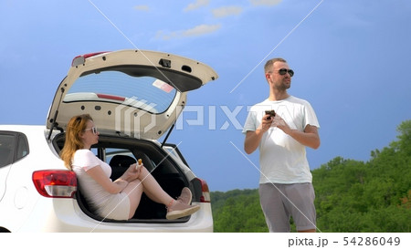 Car trip and two lovers man and woman have a snack while sitting in the trunk of a car against the Car trip and two lovers man and woman have a snack while sitting in the trunk of a car against the 54286049