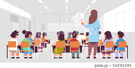 female teacher holding tests with good a grade rear view pupils group sitting in classroom during 54293395