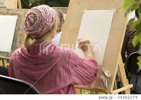 Retired woman in front of the easel in the drawing Retired woman in front of the easel in the drawing 54302274