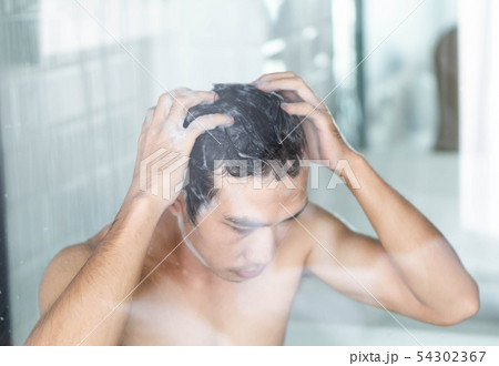 Closeup young man washing hair with with shampoo 54302367