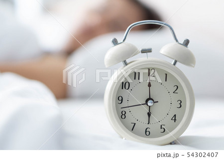 Alarm clock on white bad with light from window Alarm clock on white bad with light from window 54302407