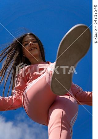 Girl in a pink sports suit against the blue sky. Girl in a pink sports suit against the blue sky. 54313540
