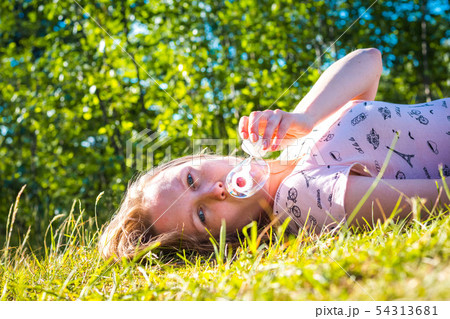 Beautiful and young girl blows soap bubbles 54313681