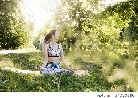 the girl is engaged in fitness and meditates in the park city the girl is engaged in fitness and meditates in the park city 54320986