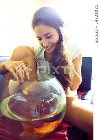 pretty woman playing with goldfish at home, sunlight morning 54321081