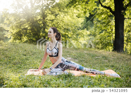 the girl is engaged in fitness and meditates in the park city 54321095