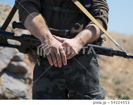 Close up view of a sniper's hands. War conflict. Close up view of a sniper's hands. War conflict. 54324553