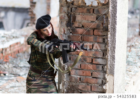 A young woman in a black beret with a gun aims at 54325583