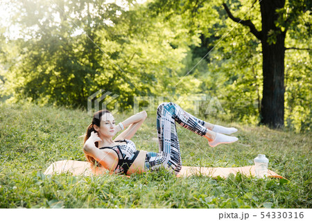 the girl is engaged in fitness and meditates in the park city the girl is engaged in fitness and meditates in the park city 54330316