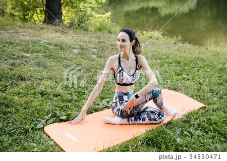 the girl is engaged in fitness and meditates in the park city 54330471