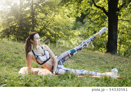 the girl is engaged in fitness and meditates in the park city the girl is engaged in fitness and meditates in the park city 54330561