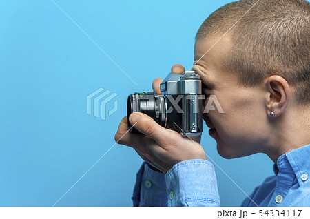 Side view of a young male photographer using vintage camera 54334117