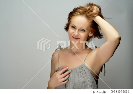 Beautiful attractive red-haired woman poses in studio on gray background. 54334635