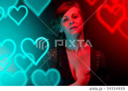 Beautiful attractive woman posing in satin bathrobe in neon light. 54334939