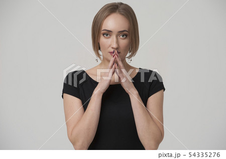 Portrait of thoughtful young woman pointing her fingers to lips 54335276