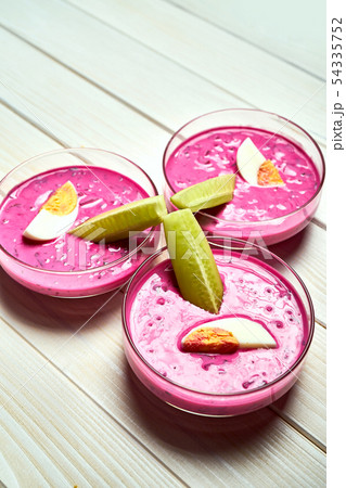 Three glass bowls with delicious cold beetroot soup on white table. Three glass bowls with delicious cold beetroot soup on white table. 54335752