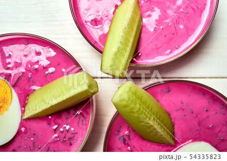 Three glass bowls with delicious cold beetroot soup on white table. 54335823