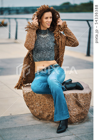Beautiful young woman posing on stone bench on the promenade at the river Beautiful young woman posing on stone bench on the promenade at the river 54336388