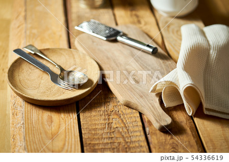 Cheese grater with fresh basil and cutlery on wooden kitchen table Cheese grater with fresh basil and cutlery on wooden kitchen table 54336619