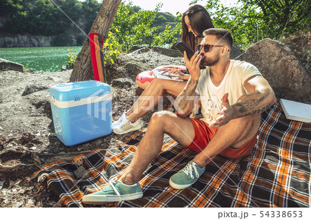 Young couple having picnic at riverside in sunny day Young couple having picnic at riverside in sunny day 54338653