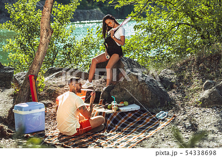 Young couple having picnic at riverside in sunny day 54338698